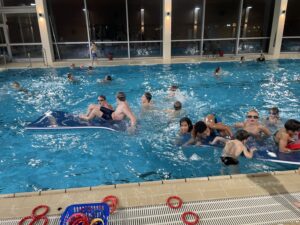 Kinder toben in einem Schwimmbecken.