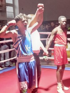 Ein Boxer jubelt, als der Kampfrichter seinen Arm zum Sieg nach oben hält.