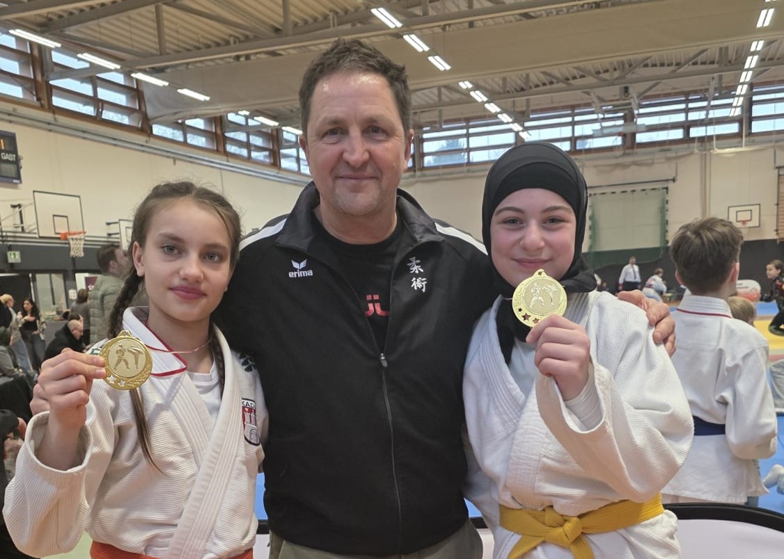 3 Personen, zwei Jugendliche mit ihren Medaillen und der Trainer in der Mitte