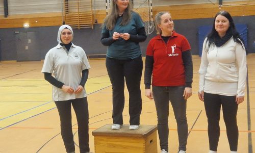 Vier Frauen bei einer Siegerehrung in einer Sporthalle.