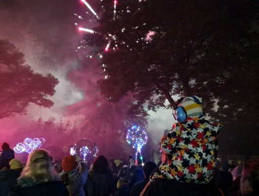 Ein Kind sitzt auf den Schultern eines Mannes und schaut sich das Feuerwerk an.