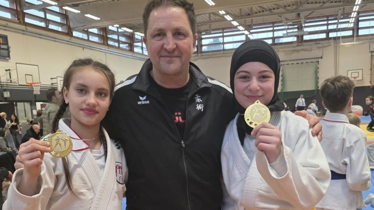 3 Personen, zwei Jugendliche mit ihren Medaillen und der Trainer in der Mitte