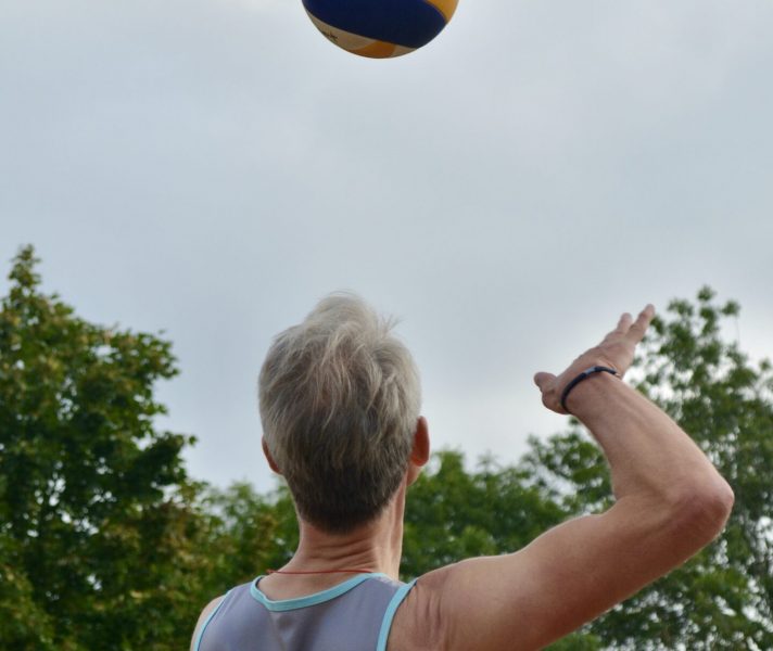 Konzentiert wirft ein Beachvolleyballer den Ball in die Luft, um die Angabe zu machen.